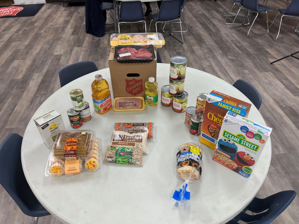Photo caption: Contents of an average food box, meat, vegetables, bread, beans, oil breakfast food, and more