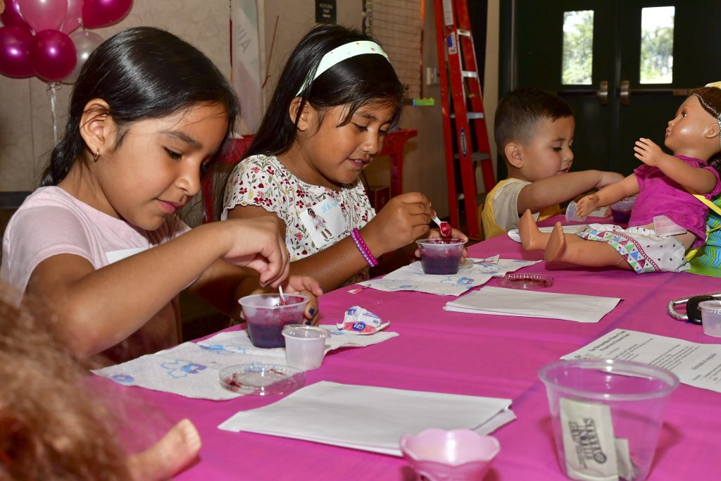 Boys and girls learned how to make their own preserves to top the scones that were served with tea. Left to right: Ariana Alvarada, Naiomy Zepeda and Emilin Zepeda. Photo by Chris Sloan